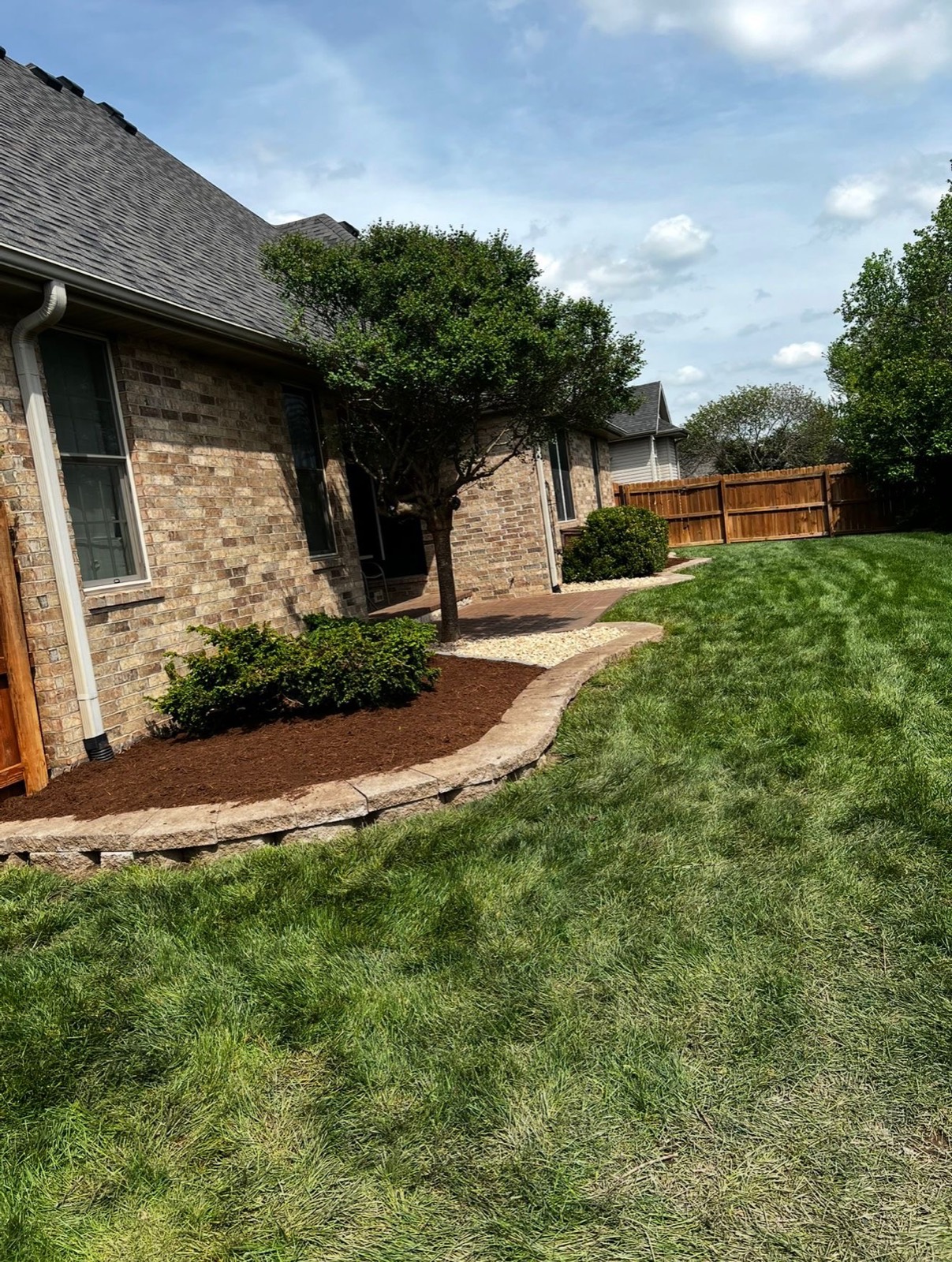 Restored mulch beds with stone edging and a healthy lawn