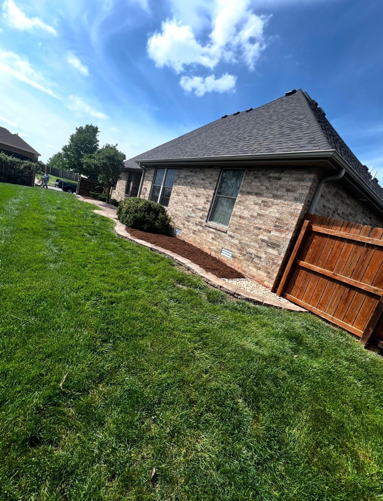 Mulched beds and thick green lawn beside a cedar fence