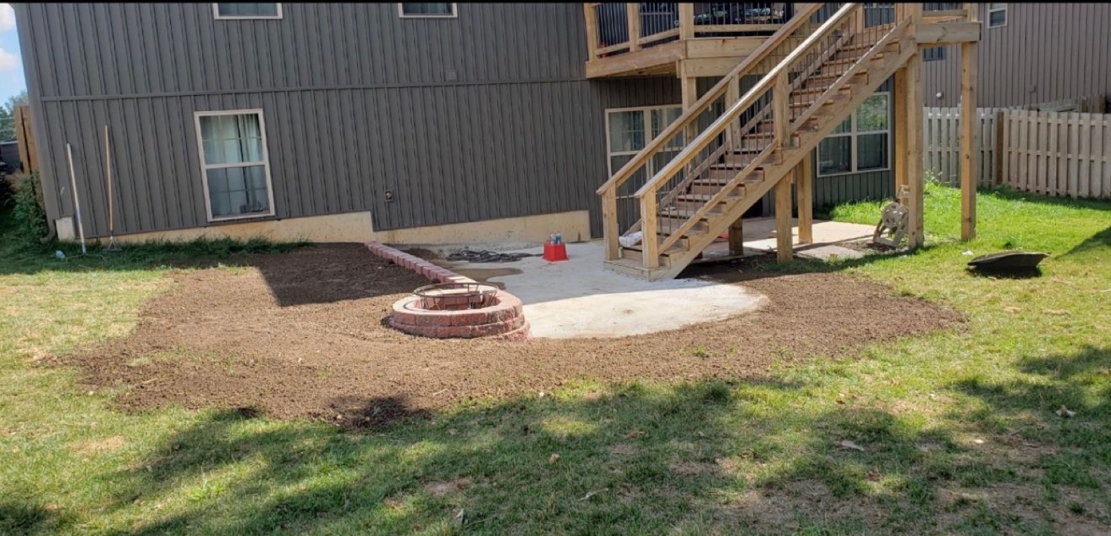 Regraded backyard with fire pit ring and prepped gravel patio